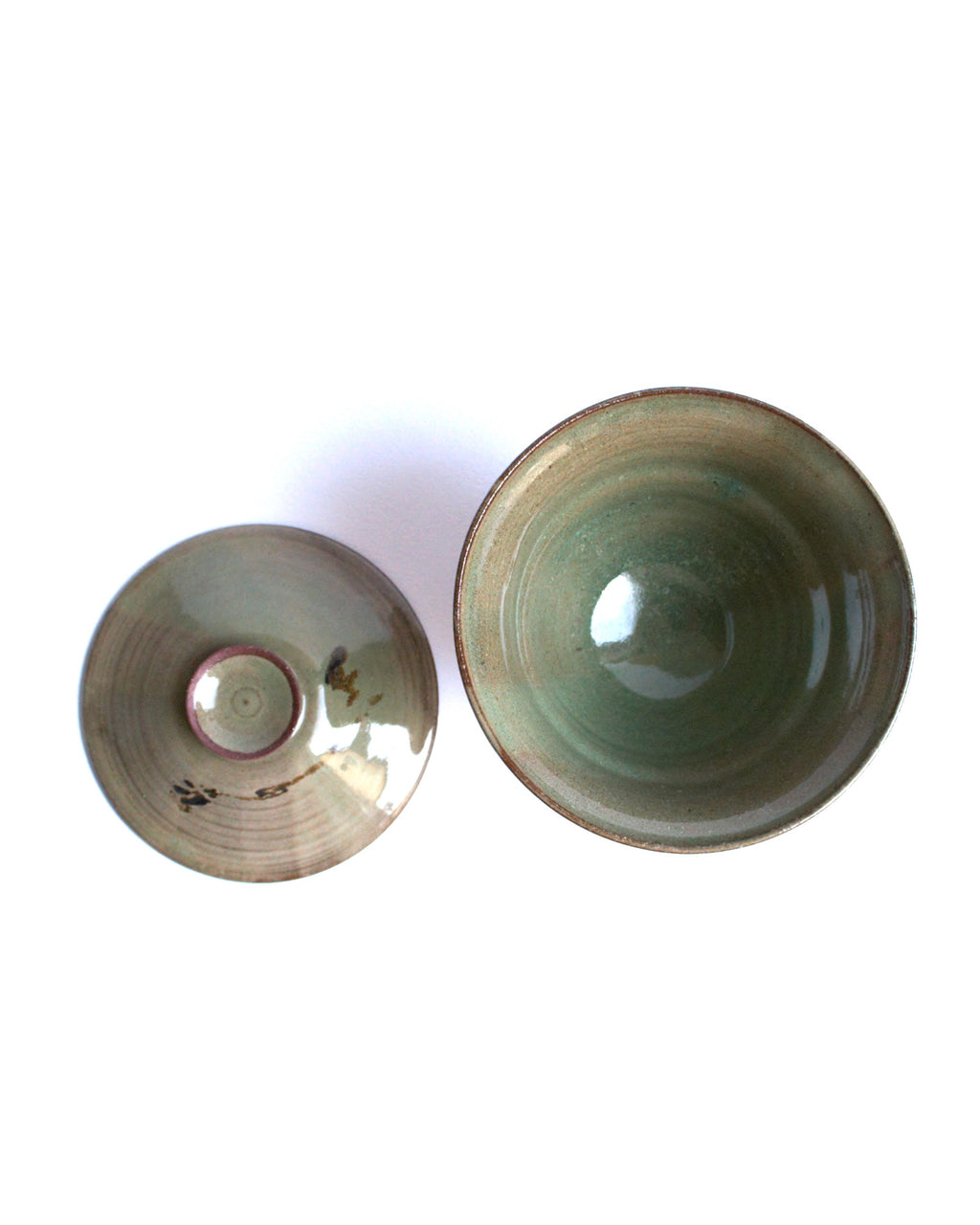 Two ceramic bowls with a greenish tint on a white background