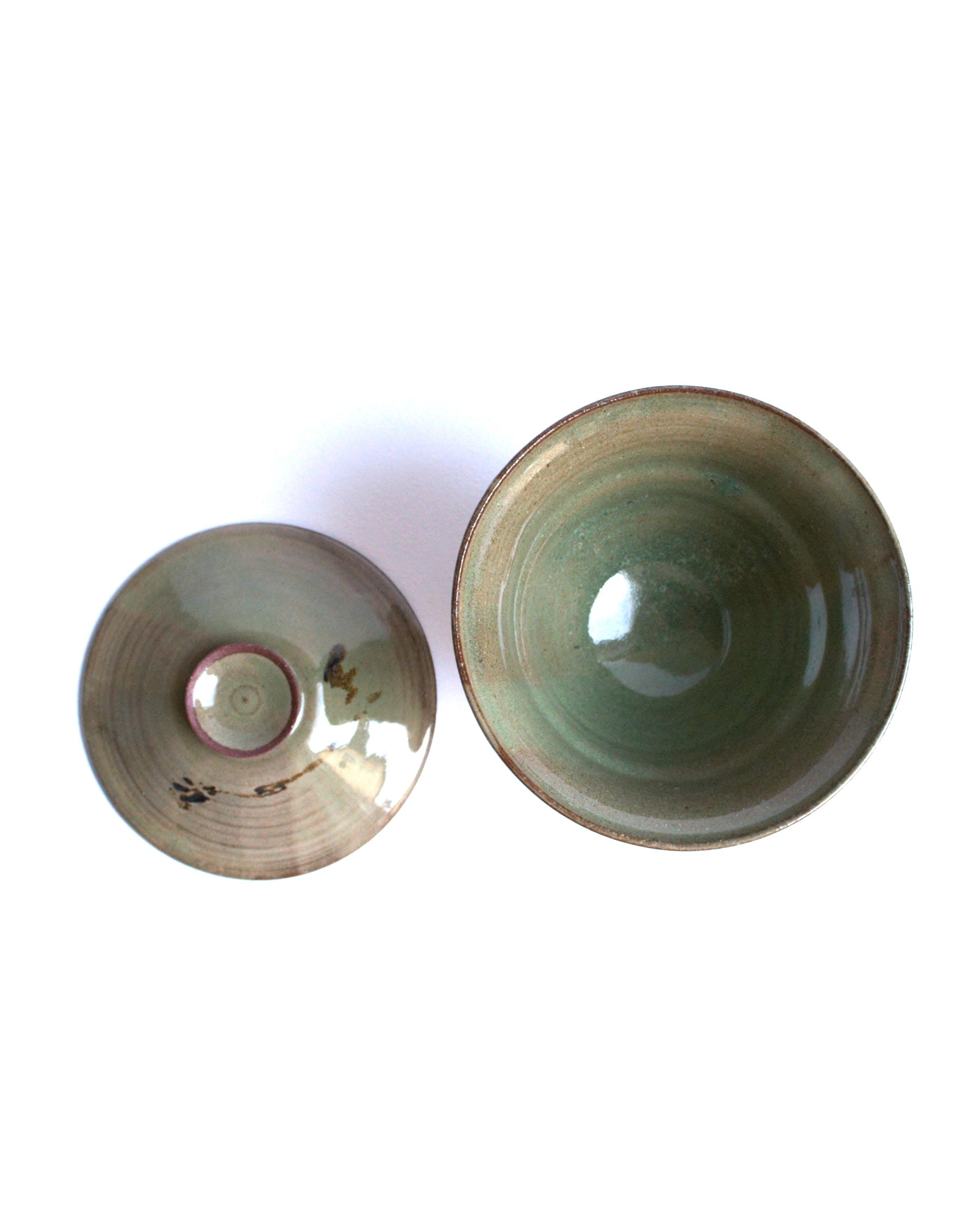 Two ceramic bowls with a greenish tint on a white background