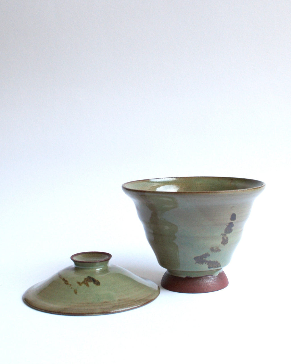 Green ceramic bowl with a matching lid on a white background